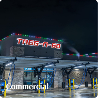 A well-lit TAGG-N-GO car wash facility at night with washing stations and festive lights along the roofline.